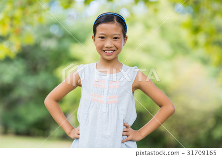 Portrait of smiling girl standing with hand on hip 31709165