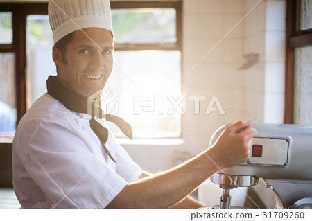 Portrait of chef blending the batter in mixing blender 31709260