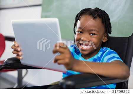 Schoolboy sitting on wheelchair and using digital tablet 31709262