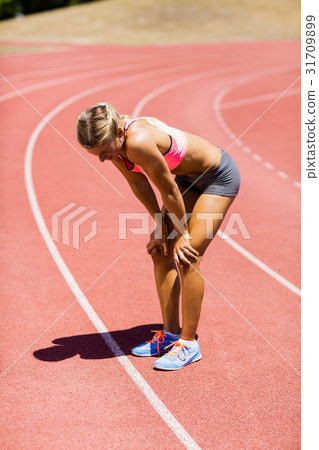 Tired female athlete standing on running track Tired female athlete standing on running track 31709899