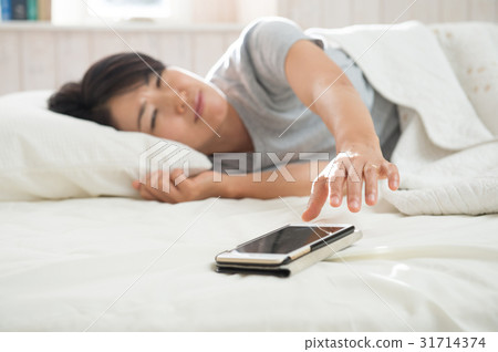 A woman waking up by an alarm A woman waking up by an alarm 31714374