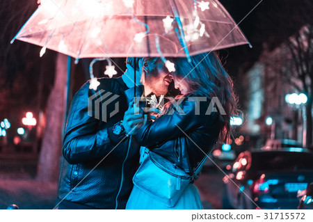 Guy and girl kissing under an umbrella Guy and girl kissing under an umbrella 31715572