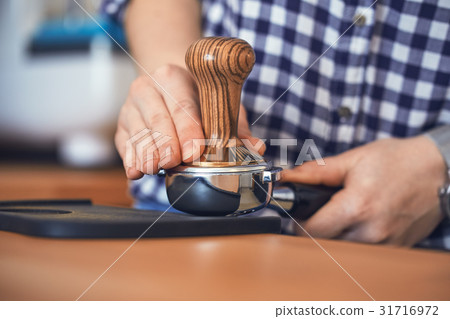 Barista tamping fresh ground coffee 31716972