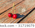 Two cherries are on a wooden table 31719079