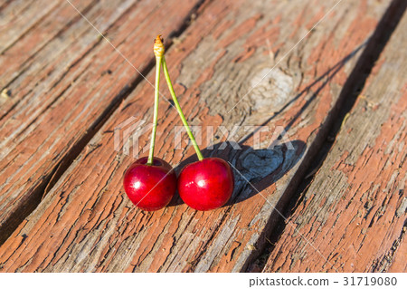 Two cherries are on a wooden table Two cherries are on a wooden table 31719080