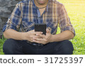Young man hands typing smartphone in the park. 31725397