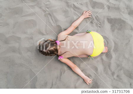 Child represents airplane lying on the sand 31731706