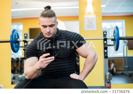 Young handsome man using phone while having Young handsome man using phone while having 31736876