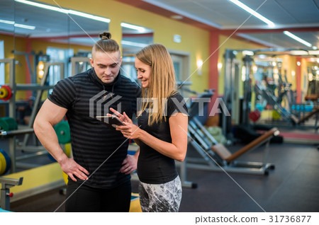 Fit attractive young couple at a gym looking at a Fit attractive young couple at a gym looking at a 31736877