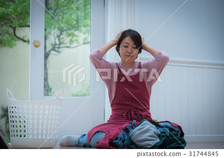 A housewife holding a head looking at the laundry 31744845