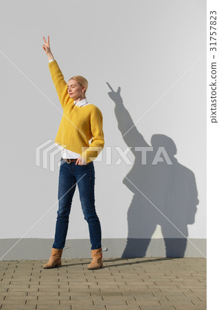 Girl posing in front of the wall with funny shadow 31757823