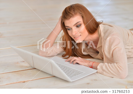 young woman lying on floor with laptop 31760253