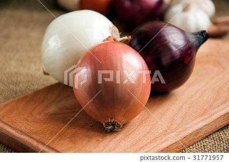 Various onions on a board on a background burlap Various onions on a board on a background burlap 31771957