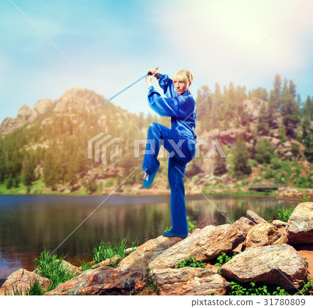 Wushu master with sword against lake and mountains 31780809