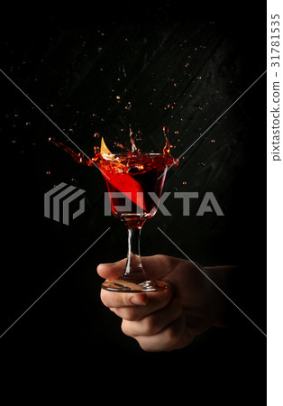 Splashing red moon cocktail in the hands. Close up Splashing red moon cocktail in the hands. Close up 31781535