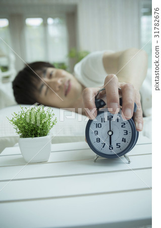 A man who stops an alarm clock 31782676
