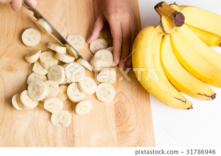Woman slice ripe banana on wooden board 31786946