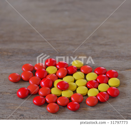Red yellow pills on old wooden table 31797773
