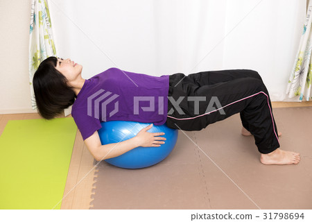 A woman who puts her back on a balance ball 31798694