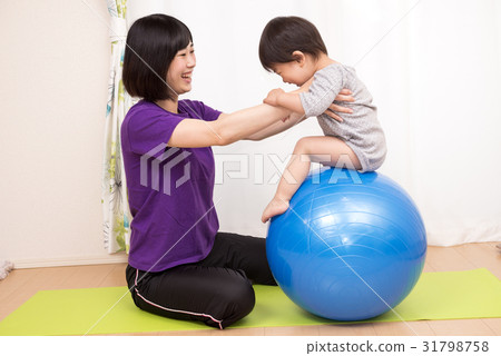The child riding the balance ball and the mother supporting it The child riding the balance ball and the mother supporting it 31798758