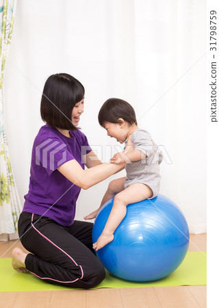 The child riding the balance ball and the mother supporting it 31798759
