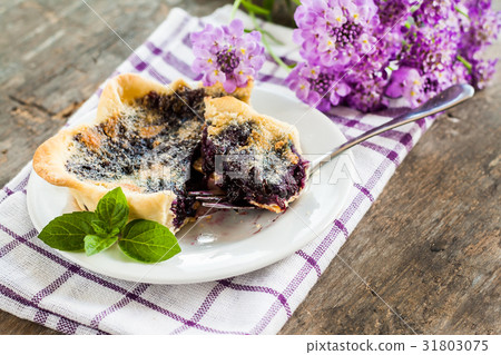 blueberry tartlet on a plate and purple flowers 31803075