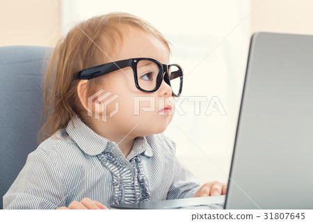 Smart little toddler girl with big glasses on her laptop Smart little toddler girl with big glasses on her laptop 31807645