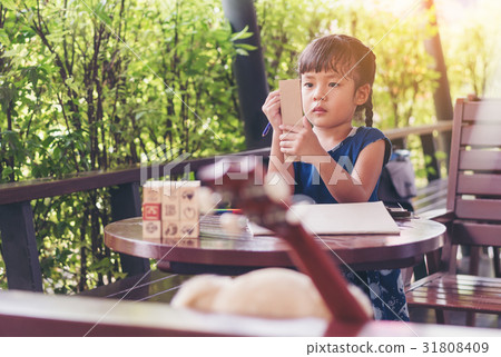 The girl's writing on paper during outdoor play. 31808409