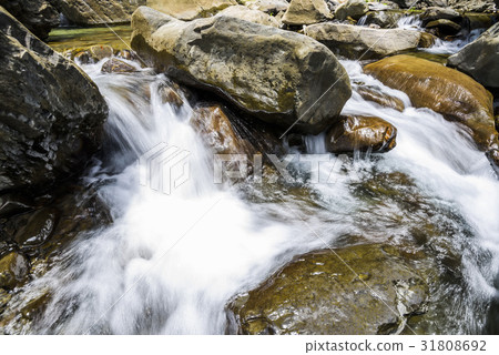 Creek or stream water flowing past rocks and stone 31808692