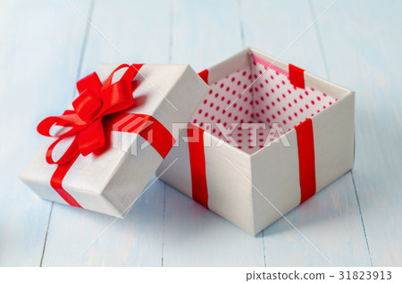 Opened gift box with red ribbon 31823913