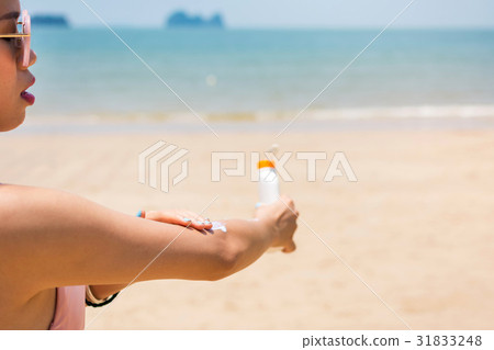 Girl applying sun lotion on the beach 31833248
