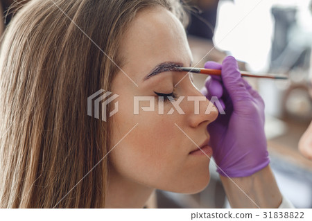 Master painting client eyebrows in the salon. 31838822