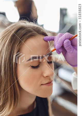 Master painting client eyebrows in the salon. 31838823