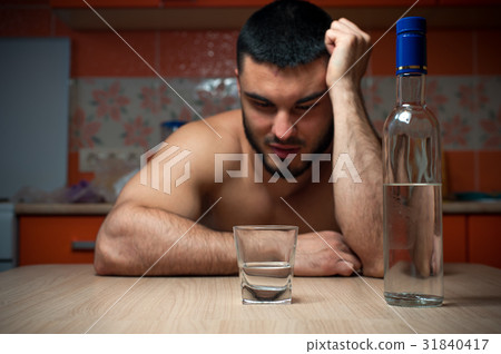 Young drunken man sitting in the kitchen at home Young drunken man sitting in the kitchen at home 31840417