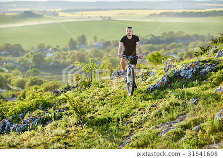 Young cyclist riding the bike on the rocky trail Young cyclist riding the bike on the rocky trail 31841608
