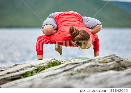Young woman doing yoga pose arm balance on the Young woman doing yoga pose arm balance on the 31842033