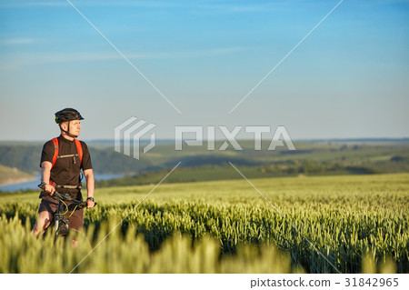 Young attractive cyclist standing up with mountain Young attractive cyclist standing up with mountain 31842965