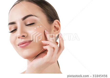 Cheery youthful lady applying facial make-up 31845456