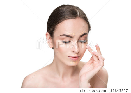Assured young lady using concealer Assured young lady using concealer 31845837