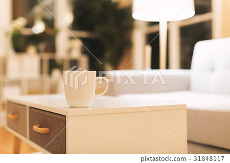 Coffee cup and gray midcentury loveseat 31848117
