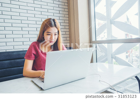 Asian girl working at a coffee shop with a laptop 31853123