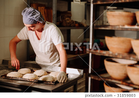 a Baker makes manual incisions on the dough for 31859803