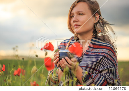 Woman in poncho with calabash on flower field Woman in poncho with calabash on flower field 31864278