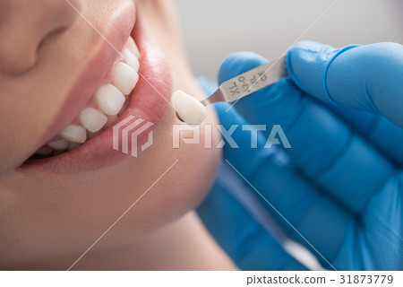 Dental crown situating near mouth of happy woman Dental crown situating near mouth of happy woman 31873779