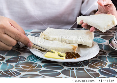 Person applying butter and kaya to steamed bread Person applying butter and kaya to steamed bread 31875136