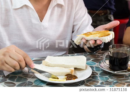 Person applying butter and kaya to steamed bread 31875138