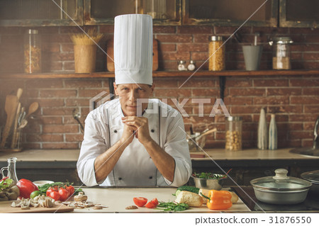 Mature man professional chef cooking meal indoors 31876550