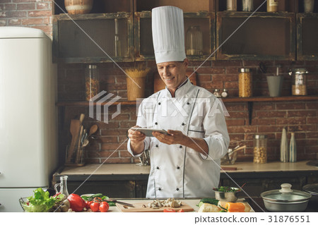 Mature man professional chef cooking meal indoors Mature man professional chef cooking meal indoors 31876551