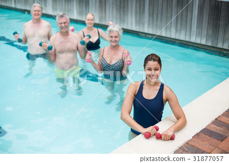 Female trainer with senior swimmers standing in pool Female trainer with senior swimmers standing in pool 31877057
