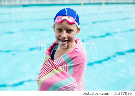 Girl wrapped in towel standing at poolside 31877080